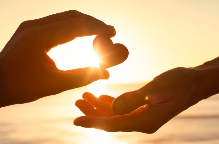 Deux mains formant un cœur au coucher du soleil